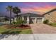 Inviting single-story home featuring a two-car garage, brick paver driveway, and lush landscaping at 8058 Corkfield Ave, Orlando, FL 32832