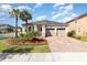Inviting single-story home featuring a two-car garage, brick paver driveway, and lush landscaping at 8058 Corkfield Ave, Orlando, FL 32832