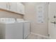 Bright laundry room with washer, dryer, storage cabinets, and a utility panel at 8058 Corkfield Ave, Orlando, FL 32832