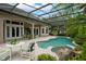 Secluded pool area with rock waterfall feature, screened enclosure, and lush tropical landscaping at 9138 Pinnacle Cir, Windermere, FL 34786