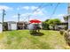 Spacious backyard with green lawn and cozy outdoor area with a red umbrella is the perfect place to relax at 1017 Florida Ave, St Cloud, FL 34769