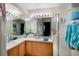Well-lit bathroom with double sinks, a large mirror, wood cabinets and a walk-in shower at 127 Lake Emma Cove Dr # 127, Lake Mary, FL 32746