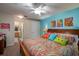 Bright bedroom with colorful bedding, artwork, and a ceiling fan, adjacent bathroom at 127 Lake Emma Cove Dr # 127, Lake Mary, FL 32746