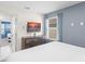 Bedroom with a large window, a wooden dresser with a TV, and an open doorway to an adjacent bedroom at 2009 Tropical Palms Cir, Kissimmee, FL 34747