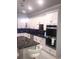 Modern kitchen featuring stainless steel appliances, including double ovens, white cabinetry, and black marble countertops at 2300 Painter Ln, Kissimmee, FL 34741