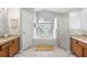 Bright bathroom featuring double sinks, soaking tub under arched window, and tiled floor at 3016 Samosa Hill Cir, Clermont, FL 34714