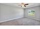 Bedroom with tray ceiling, ceiling fan, gray carpet and trim, and a large window at 4126 Sw 132Nd Ln, Ocala, FL 34473