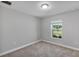 A bright bedroom with neutral walls, plush carpet, a window with a view, and modern lighting at 4126 Sw 132Nd Ln, Ocala, FL 34473