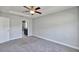 Bedroom featuring ceiling fan, gray carpet and trim, and entry way to a bathroom at 4126 Sw 132Nd Ln, Ocala, FL 34473