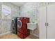 Bright laundry room featuring modern washer and dryer units, sink, shelving, and whimsical wallpaper at 618 Crownclover Ave, Orlando, FL 32828