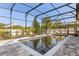 Screened-in pool with a uniquely-shaped design surrounded by a neutral stone patio at 618 Crownclover Ave, Orlando, FL 32828