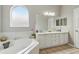 Bright bathroom featuring a soaking tub under a large arched window, a dual sink vanity, and tile floors at 9915 Kona Isle Ct, Orlando, FL 32817