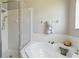 Bathroom showcasing a glass-enclosed shower, soaking tub with decorative accents, and white tiled walls at 9915 Kona Isle Ct, Orlando, FL 32817