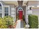 Inviting entryway features a red front door, tiled floor, manicured landscaping, and stylish exterior lighting at 9915 Kona Isle Ct, Orlando, FL 32817