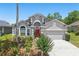 Charming single-Gathering home featuring a well-maintained lawn, flowering plants, and a red front door at 9915 Kona Isle Ct, Orlando, FL 32817