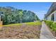 View of the spacious, tree-lined backyard, showcasing a walkway, fence, and verdant greenery at 1003 Shore Dr, Kissimmee, FL 34744