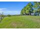 Beautiful waterfront view featuring a large grassy yard, wood fence, and majestic trees at 1003 Shore Dr, Kissimmee, FL 34744