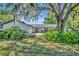 Charming one-story home with a well-maintained lawn and large, mature trees draped with Spanish moss at 1003 Shore Dr, Kissimmee, FL 34744