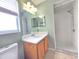 Bathroom with a single sink vanity, mirror, and a walk-in shower with tiled floors and walls at 10235 Summer Elm Ave, Clermont, FL 34711