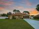 Charming single-story home boasts a well-manicured lawn and two-car garage, with a picturesque sunset backdrop at 10235 Summer Elm Ave, Clermont, FL 34711