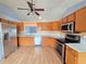 Well-equipped kitchen boasts stainless steel appliances, wood cabinets, and laminate flooring for easy maintenance and modern appeal at 10235 Summer Elm Ave, Clermont, FL 34711