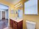 Bathroom featuring a cherry wood vanity, large mirror, and view to another room at 12822 Moss Park Ridge Dr, Orlando, FL 32832
