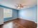 Bedroom features wood floors, blue walls, ceiling fan, and window for natural light at 12822 Moss Park Ridge Dr, Orlando, FL 32832