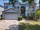 Charming two-story blue home with landscaped yard and brick driveway and a two-car garage at 12822 Moss Park Ridge Dr, Orlando, FL 32832
