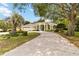 Elegant single-story home featuring a curved driveway, manicured lawn, and a mature shade tree at 1320 Antrim Cir, Ormond Beach, FL 32174