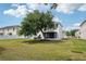 Large backyard with a mature shade tree, screened in lanai, and comfortable seating area with blue chairs at 1986 Yellowfin Dr, Port Orange, FL 32128