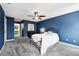 Bedroom with blue walls featuring a ceiling fan, carpeted floors, and ensuite bathroom at 1986 Yellowfin Dr, Port Orange, FL 32128