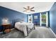 Bedroom with blue walls featuring ceiling fan, carpeted floors, and sun-filled windows with white curtains at 1986 Yellowfin Dr, Port Orange, FL 32128