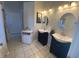 This bathroom features tile floors, two sinks with black cabinets, vanity lighting, and oval mirrors at 2236 Dancy Trail Trl, Clermont, FL 34714