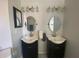 This bathroom features two sinks with black cabinets, vanity lighting, and oval mirrors at 2236 Dancy Trail Trl, Clermont, FL 34714