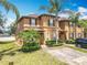 Inviting townhome with lush landscaping, brick driveway, and charming curb appeal under a sunny sky at 2744 Calabria Ave, Davenport, FL 33897