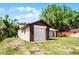 View of the detached garage with white door featuring brick trim, set in a grassy yard at 288 Howard Blvd, Longwood, FL 32750