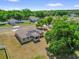 An aerial view shows a tan home with a screened in porch under a partly cloudy blue sky at 326 Woodland Trl, Lady Lake, FL 32159