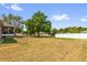 Spacious backyard with lush green grass, mature trees, a white fence, and a screened porch at 326 Woodland Trl, Lady Lake, FL 32159