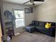 Bedroom featuring a large window, ceiling fan, shelving, and a comfortable gray sectional couch at 326 Woodland Trl, Lady Lake, FL 32159