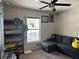 Cozy bedroom featuring a large window, ceiling fan, and a comfortable gray sectional couch at 326 Woodland Trl, Lady Lake, FL 32159
