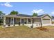 Inviting single-story home featuring a covered porch with rocking chairs and neat landscaping at 326 Woodland Trl, Lady Lake, FL 32159