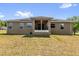 Rear view of home with screened porch, neutral siding, and well-manicured lawn at 326 Woodland Trl, Lady Lake, FL 32159