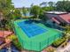 Aerial view of a tennis court surrounded by a green fence with trees and a lake in the background at 5112 Conroy Rd # 13, Orlando, FL 32811