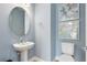 Powder room with modern fixtures, pedestal sink, round mirror, and light blue walls with decorative artwork at 5262 Foothills Preserve Loop, Mount Dora, FL 32757