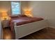 Bright bedroom features a white frame bed, patterned comforter, a nightstand with lamp, and a window for natural light at 7415 Devereaux St, Reunion, FL 34747