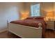 Bright bedroom features a white frame bed, patterned comforter, a nightstand with lamp, and a window for natural light at 7415 Devereaux St, Reunion, FL 34747