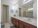 Bathroom with double sinks, a shower, and a toilet in a well-lit room with decorative artwork on the walls at 9007 Pelican Cove Trce, Kissimmee, FL 34747