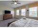 Bedroom with a king-size bed, wooden dresser, and large windows with views of the outdoors at 9007 Pelican Cove Trce, Kissimmee, FL 34747