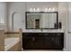 Bathroom featuring double vanity, tub, and a walk-in closet with custom shelving at 9405 Bordet Ct, Orlando, FL 32827
