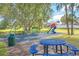 Community playground with a slide, swings, picnic table, and a safety surface for recreational activities at 115 Oak Grove Cir, Lake Mary, FL 32746